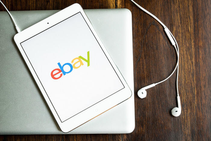Ebay-Logo auf einem Smartphone, das auf einem Laptop liegt