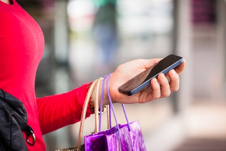 Frau mit Smartphone in der Hand beim Shopping