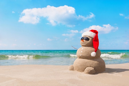 Schneemann aus Sand am Strand mit Weihnachtsmann-Mütze