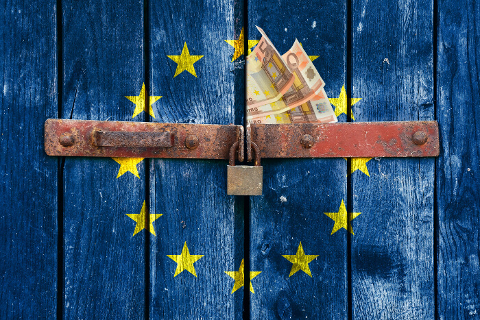 EU-Flagge auf verschlossenem Tor mit Geldscheinen