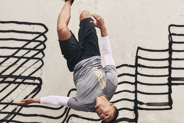 Sportlicher Mann macht ein Rückwärts-Salto vor einer mit Graffiti besprühten Wand