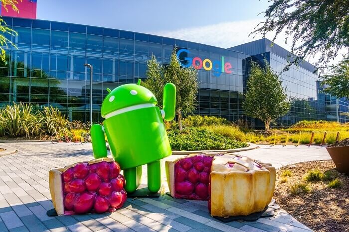 Android Maskottchen mit angeschnittenen Kuchen steht vor Android-Firmenzentrale