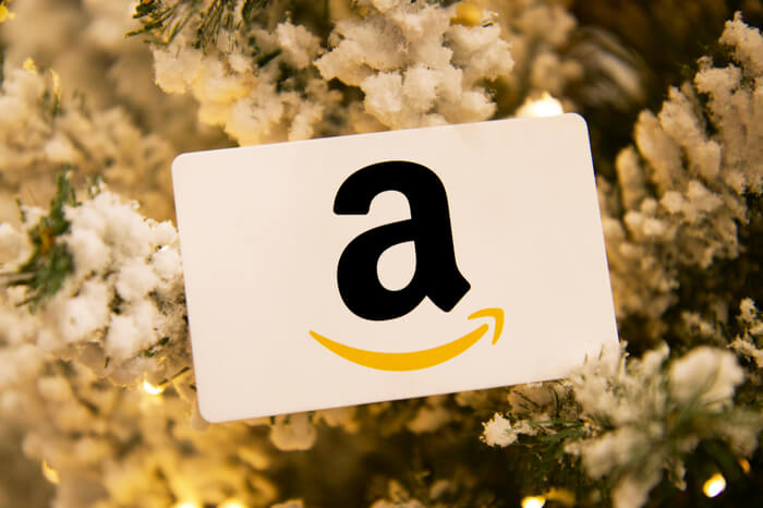 Amazon-Logo mit Weihnachtsbaum im Hintergrund