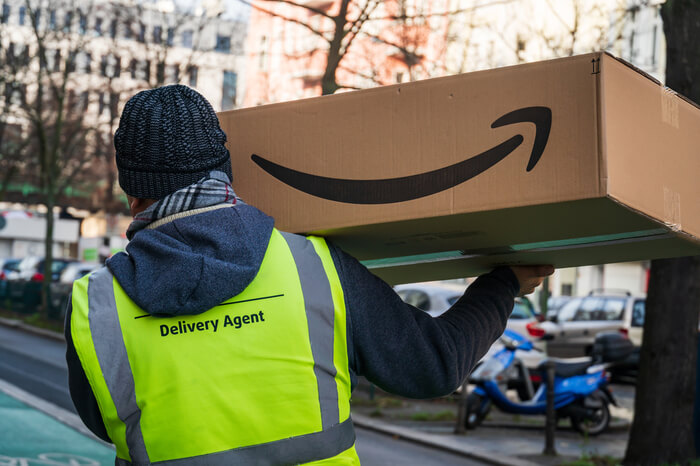 Zusteller trägt Amazon-Paket