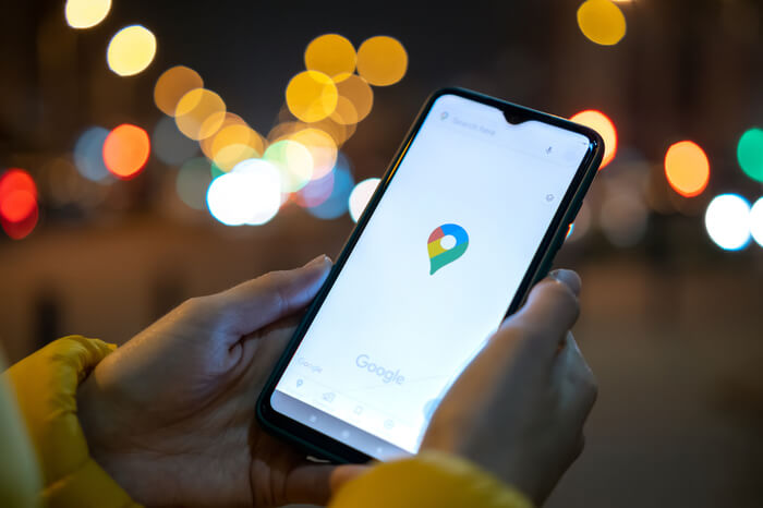 Mobiltelefon mit Google Maps-Navigationsanwendung vor nächtlichem Hintergrund