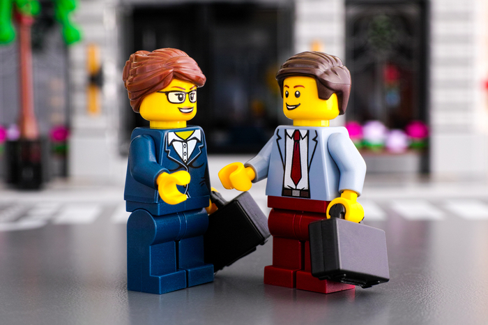 Zwei Legofiguren, die wie ein Geschäftsmann und eine Geschäftsfrau aussehen, geben sich die Hand.