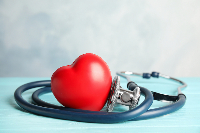 Stethoskop und rotes Herz auf Holztisch