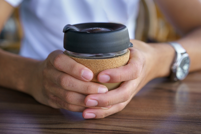 Hände halten wiederverwendbaren Kaffeebecher