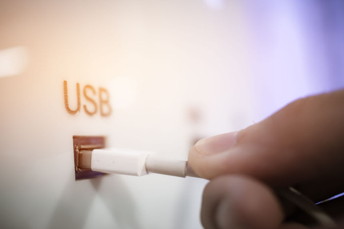 Hand steckt USB-Kabel in Zugang