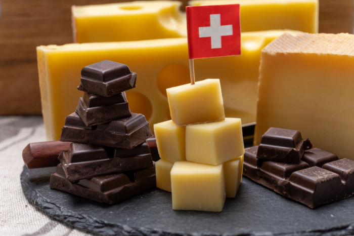 Emmentaler und Schokolade mit kleiner Schweizer Flagge auf Steinplatte