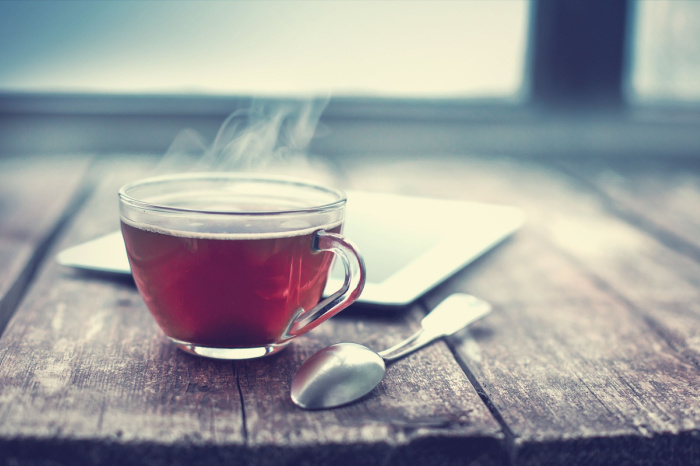 Tasse mit schwarzem Tee auf Holztisch