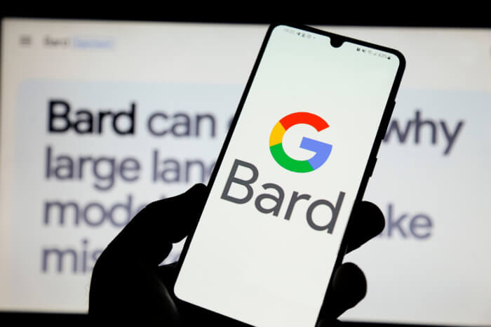 Google-Bard-Logo auf Smartphone vor Website mit Chatbot