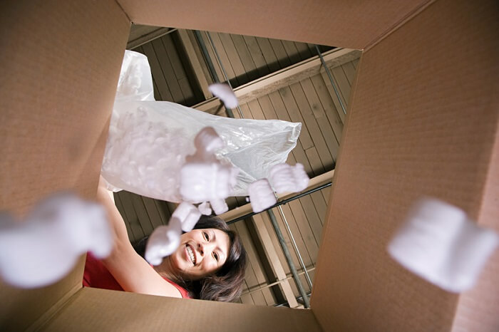 Frau kippt Verpackungsmaterial in Karton