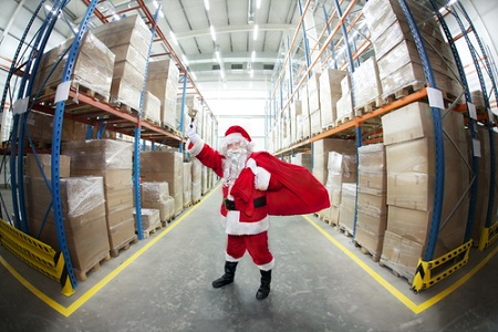 Santa Claus with red sack , ringing in a bell in storehouse full of gifts