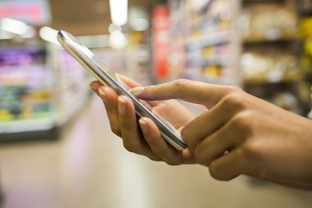 Frau nutzt Smartphone im Supermarkt