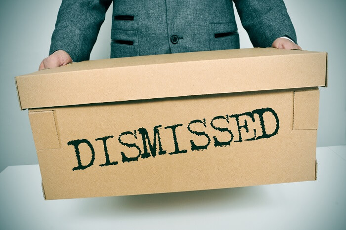 a businessman carrying a box with the word dismissed written in it