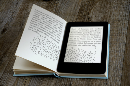 modern ebook reader on book on wooden background