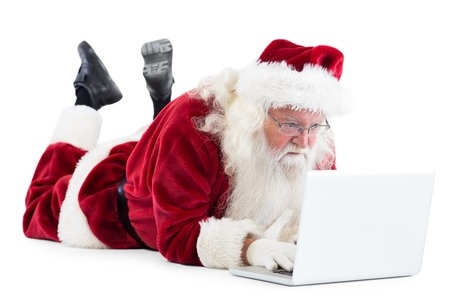 Santa lies in front of his laptop on white background