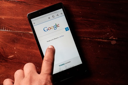 Smartphone liegt auf Tisch mit Google Startseite 