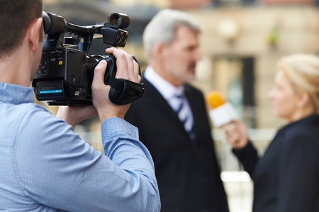 Kameramann nimmt Journalistin auf, wie sie einen Geschäftsmann interviewt