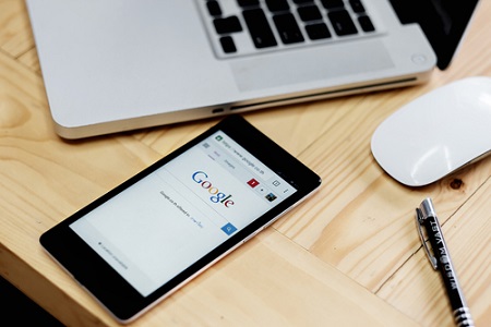 Google auf Smartphone neben Laptop