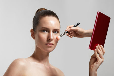 Frau wird aus einem Tablet heraus geschminkt