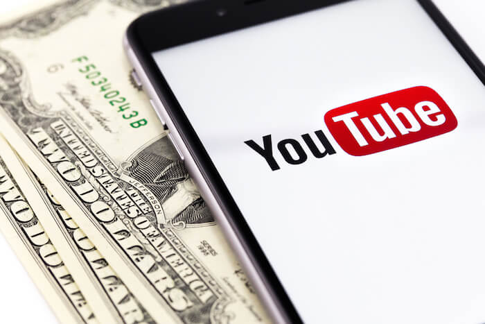 YouTube auf einem Smartphone neben Geld