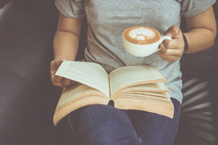 Lady liest Buch und trinkt Kaffee